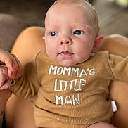 Kolton joined the competition — help win amazing prizes! baby, infant, onesie, clothing, hand, holding, face, blue_eyes, skin, person, closeup, expression, small_fingers, blurred_background, indoor, cute, child, newborn, human, portrait