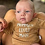 baby, infant, onesie, clothing, hand, holding, face, blue_eyes, skin, person, closeup, expression, small_fingers, blurred_background, indoor, cute, child, newborn, human, portrait