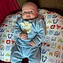 baby, infant, blue_clothing, giraffe_applique, pillow, animal_print, smile, face, child, cozy, socks, seated, indoor, cute, person, home, furniture, patterned, comfort, soft