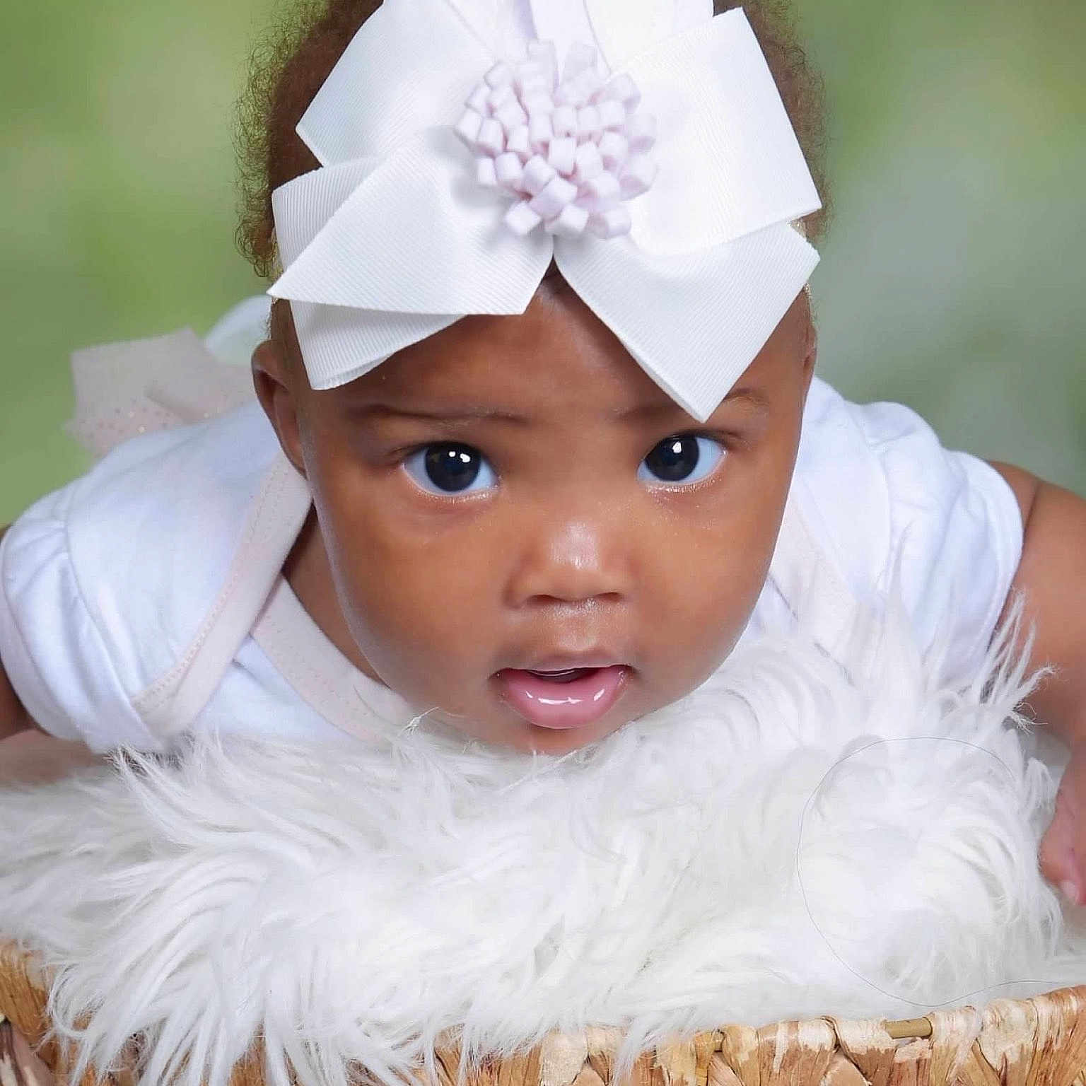 Nova is registered to the contest to win money with this photo: baby, child, close_up, clothing, curious, cute, expression, eyes, face, fluffy_blanket, headband, indoor, infant, mouth, person, portrait, skin, soft_lighting, white_bow, wicker_basket