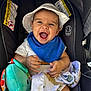 baby, child, car_seat, hat, blue_bib, plush_toy, blanket, smiling, happy, infant, sitting, toy, clothing, face, person, safety_warning, indoor, cute, headwear, closeup