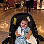 baby, car_seat, blanket, smiling, indoor, people, floor, lighting, furniture, child, person, happy, clothing, infant, seat, warm_light, background, walking, standing, casual