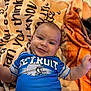 Jireh is registered to the contest to win money with this photo: baby, infant, smiling, blue_shirt, detroit, blanket, text_on_blanket, floor_tiles, cute, child, lying_down, happy, young_child, indoor, portrait, arm, head, face, skin, person