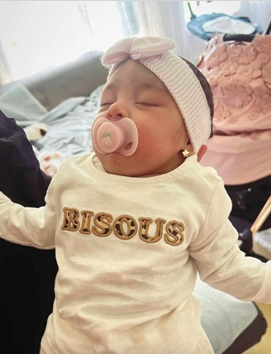 Eva Maria participe au concours pour gagner de l'argent avec cette photo : baby, pacifier, headband, white_clothing, sleeping, indoor, child, earrings, cute, infant, soft_lighting, resting, person, cozy, shirt, text_on_clothing, pink, decor, furniture, peaceful