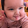 baby, infant, child, portrait, close_up, face, smiling, tongue_out, rosy_cheeks, blue_eyes, brown_hair, pink_clothing, bib, long_sleeves, hand, indoor, cozy, happy, adorable, photography