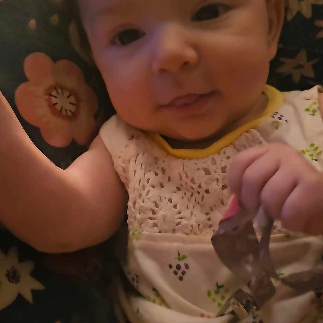 Crimson is registered to the contest to win money with this photo: applique, baby, bodypart, clothing, couch, cushion, cutlery, dress, face, finger, fork, furniture, hand, head, homedecor, person, photography, portrait, quilt, spoon