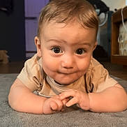 Anakin is registered to the contest to win money with this photo: baby, carpet, child, clothing, curious, cute, expression, eyes, face, hair, hands, home, indoor, infant, lighting, lying_down, portrait, smile, soft_texture, young