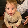 adult_support, baby, beige, boots, bright_eyes, brown, child, clothing, costume, cute, floor, hands, happy, indoors, infant, person, portrait, sitting, smile, young_child