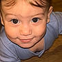 baby, blue_clothing, child, close_up, crawling, cute, eyes, face, floor, hair, happy, head, indoors, infant, one_person, portrait, skin, smiling, wooden_floor, young_child