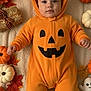 autumn_leaves, baby, blanket, candle, costume, cozy, cute, fall_decoration, festive, ghost_toy, halloween, holiday, infant, jack_o_lantern, laying_down, orange, pumpkin_costume, seasonal, smiling, white_pumpkin