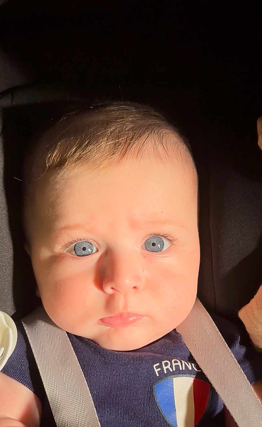 Nael participe au concours pour gagner de l'argent avec cette photo : baby, blue_eyes, face, infant, close_up, child, skin, hair, clothing, straps, sunlight, portrait, expression, cute, young, person, looking_at_camera, soft_light, indoor, apparel