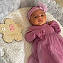 baby, infant, pink_dress, headband, flower, wooden_plaque, milestone, two_months, blanket, stars, soft_texture, cushion, lying_down, indoors, child, cute, portrait, newborn, fabric, resting