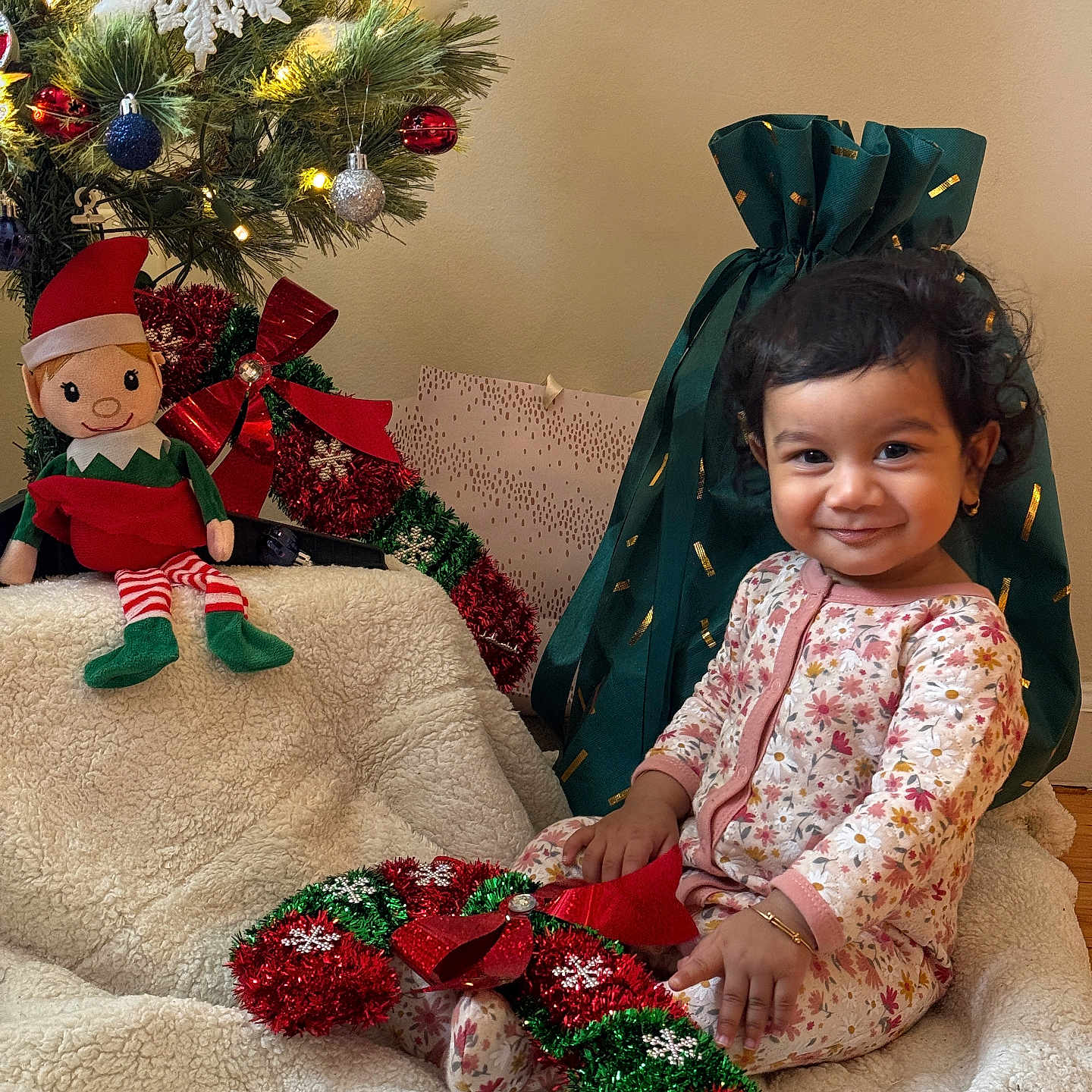 Narayan joined the competition — help win amazing prizes! blanket, child, christmas_tree, cozy, earring, festive, garland, gift_bag, holiday, ornament, pajamas, plush_toy, portrait, present, ribbon, smile, snowflake_ornament, stuffed_elf, toddler, wooden_floor