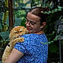 woman, cat, glasses, blue_dress, fluffy_cat, orange_cat, indoor_garden, plants, greenery, pet, holding, portrait, animal, cute, expression, nature, casual, happy, love, affection