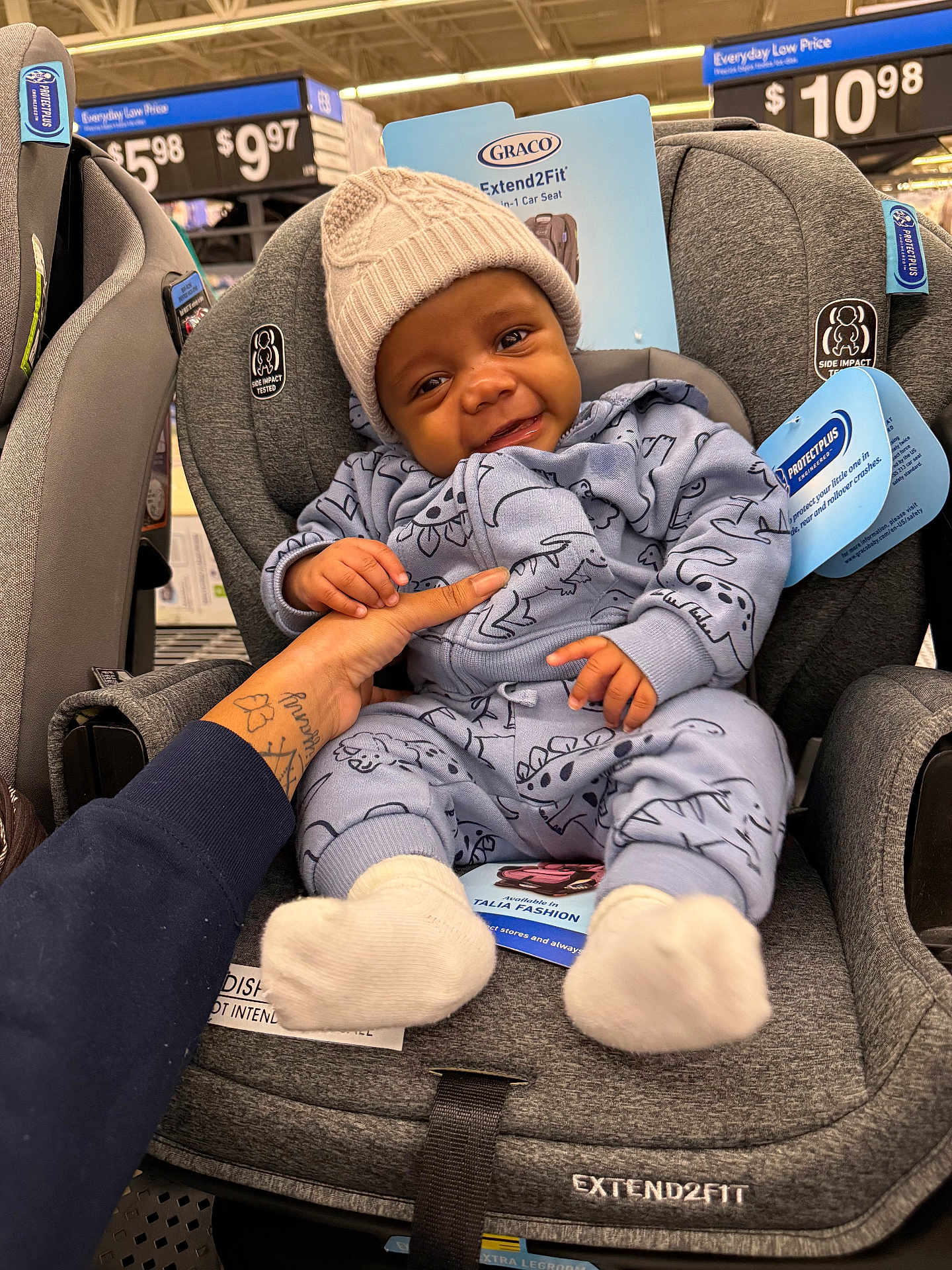 Zackaron joined the competition — help win amazing prizes! baby, infant, car_seat, clothing, hat, smile, hand, store, price_tag, display, product_label, dinosaur_pattern, knit_hat, socks, gray, child, person, cute, indoor, holding