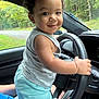 Ryland joined the competition — help win amazing prizes! child, toddler, curly_hair, smiling, car_interior, steering_wheel, driving, window, greenery, forest, casual_clothing, tank_top, shorts, person, road, daylight, cute, happy, portrait, indoors