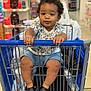 Ryland is registered to the contest to win money with this photo: baby, shopping_cart, child, grocery_store, curly_hair, blue_shorts, black_shoes, white_shirt, indoor, person, holding, shopping, retail, seat, hands, footwear, expression, cute, store_aisle, plastic_bag