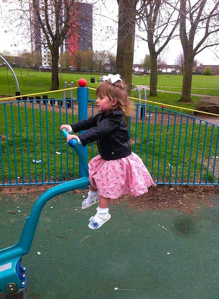 Gracie is registered to the contest to win money with this photo: child, city, fence, fun, garden, grass, lawn, leisure, magenta, outdoor_play_equipment, people_in_nature, person, plant, play, playground, recreation, riding_toy, sky, toddler, tree