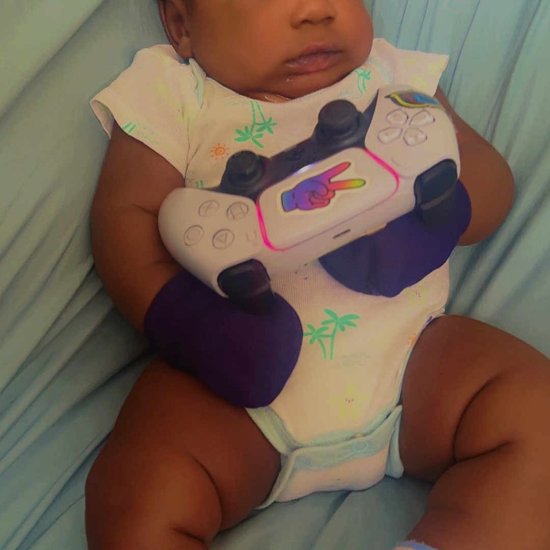 Arthur Chery is registered to the contest to win money with this photo: baby, blue_blanket, child, chubby_legs, closeup, curious, cute, expression, feet, gaming_controller, hands, indoor, infant, mittens, onesie, portrait, relaxed, seated, socks, soft_lighting