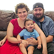 Robin joined the competition — help win amazing prizes! family, baby, woman, man, couch, smile, happy, indoor, casual_clothing, red_dress, cap, beard, parent, child, portrait, seated, leather_furniture, tattoo, short_hair, holding