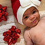 baby, blanket, cheeks, cute, face, festive, hand, happy, holiday, holiday_decor, infant, knit_hat, lying_down, portrait, red_gift_bows, red_hat, skin, smiling, soft_texture, white_bow