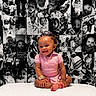 baby, background, black_and_white, child, collage, cute, decor, happy, indoor, infant, joyful, people, photography, pink_clothing, portrait, sitting, smiling, table, toddler, young_child