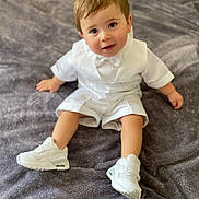 Lucca is registered to the contest to win money with this photo: toddler, child, white_outfit, bow_tie, sneakers, sitting, gray_blanket, cute, portrait, indoors, baby, smiling, happy, young_child, fashion, footwear, soft_texture, casual, person, closeup