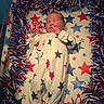 newborn, baby, crib, onesie, stars, red, white, blue, pinwheel, garland, sleeping, infant, pattern, decor, celebration, holiday, cute, face, hand, footed_pajamas