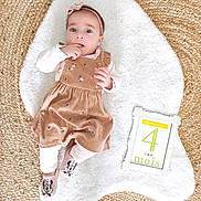 Sofia participe au concours pour gagner de l'argent avec cette photo : baby, infant, girl, dress, headband, socks, minnie_mouse, floral, white_rug, woven_mat, frame, sign, 4_months, cute, lying_down, child, indoors, soft_texture, pink, brown