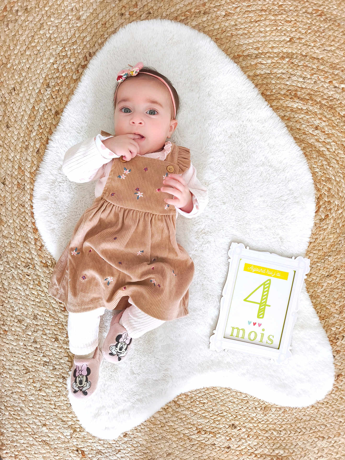 Sofia participe au concours pour gagner de l'argent avec cette photo : baby, infant, girl, dress, headband, socks, minnie_mouse, floral, white_rug, woven_mat, frame, sign, 4_months, cute, lying_down, child, indoors, soft_texture, pink, brown