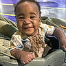 baby, child, smiling, happy, portrait, stroller, indoor, playground, amusement_park, colorful, curly_hair, infant, sitting, front_facing, casual_clothing, bib, toy_print, family_outing, close_up, photography