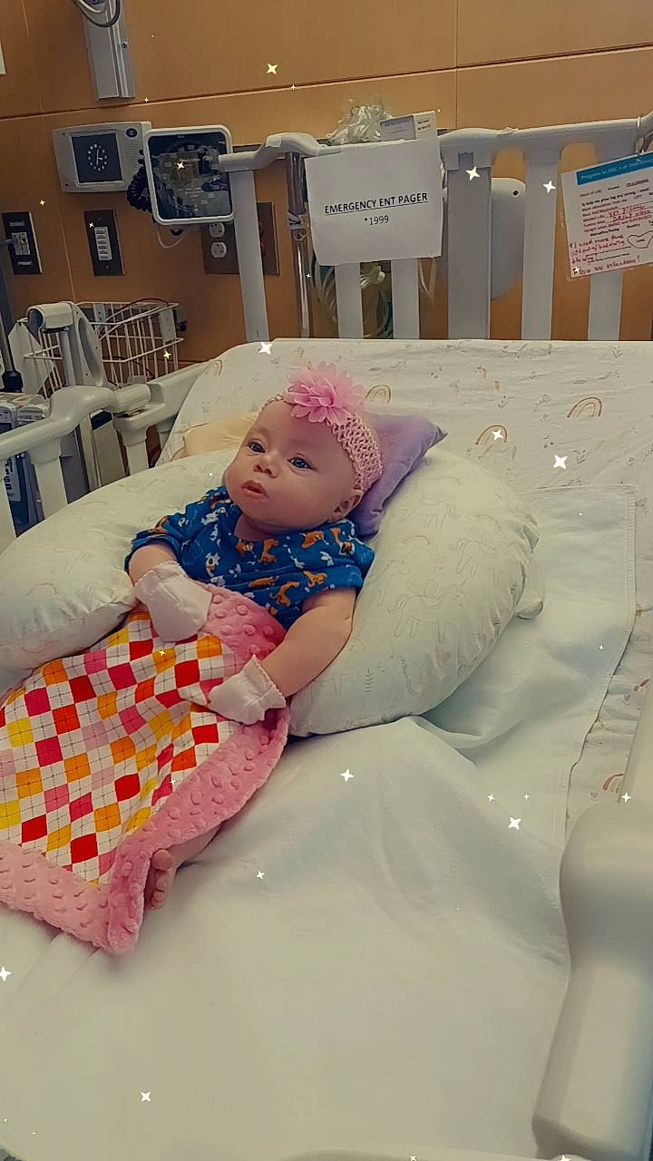 Elana is registered to the contest to win money with this photo: baby, baby_toddler_clothing, bedding, chair, child, comfort, event, fun, happy, hat, linens, pattern, person, pink, room, sitting, textile, toddler