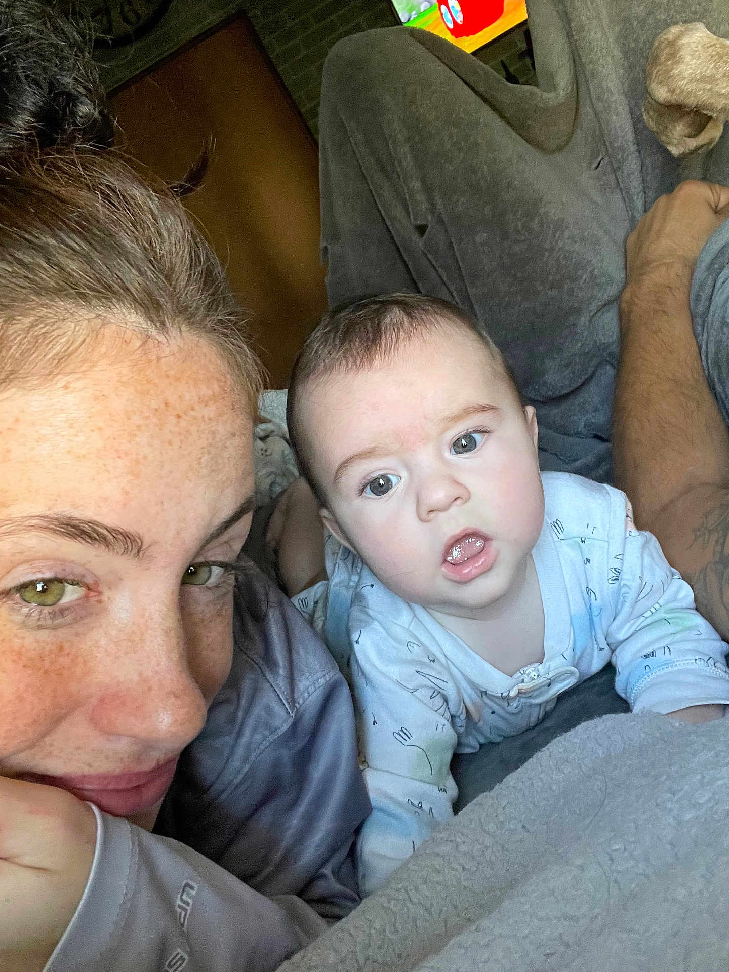 Hudson is registered to the contest to win money with this photo: baby, woman, freckles, blanket, indoor, face, closeup, expression, curious, child, person, skin, hair, eyes, portrait, casual, laying, clothing, toddler, relaxed