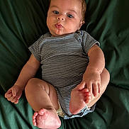 Oliver is registered to the contest to win money with this photo: baby, blanket, child, chubby, curious, cute, expression, face, feet, green_background, hands, human, indoors, infant, lying_down, onesie, portrait, skin, soft_lighting, striped_clothing