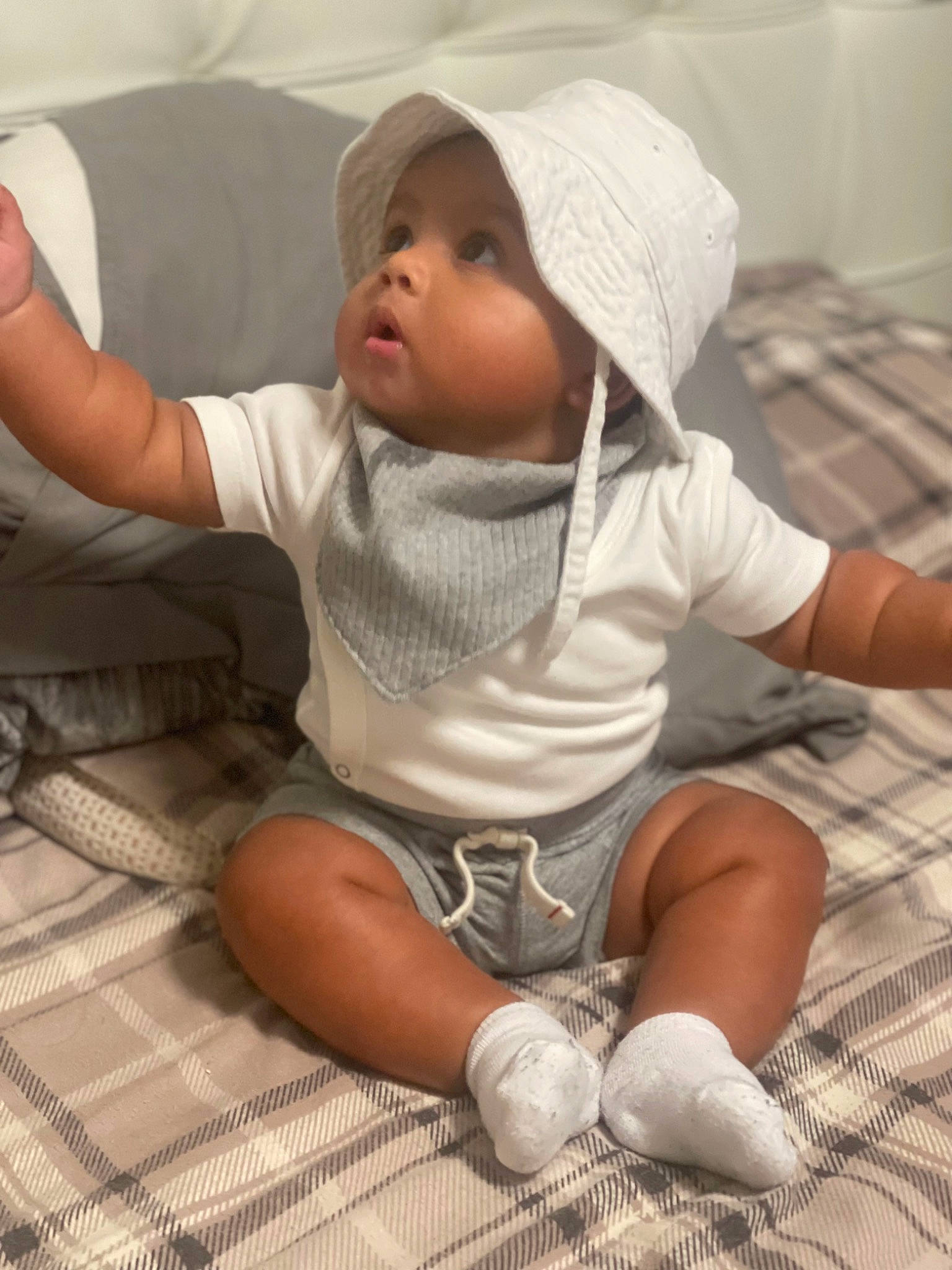 Luka is registered to the contest to win money with this photo: baby, baby_toddler_clothing, barefoot, child, comfort, face, finger, flooring, foot, headwear, human_leg, knee, leg, linens, person, shorts, sitting, skin, sleeve, sock