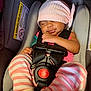 baby, sleeping, car_seat, pink_hat, striped_pants, socks, infant, child, resting, seatbelt, safety, cute, adorable, newborn, peaceful, indoors, closeup, young_child, baby_clothes, transport