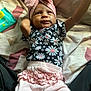 Nakiea is registered to the contest to win money with this photo: baby, infant, child, headwrap, bow, floral_shirt, pink_pants, ruffles, bedspread, pattern, indoor, person, cute, reaching, lying_down, clothing, fabric, skin, face, arm