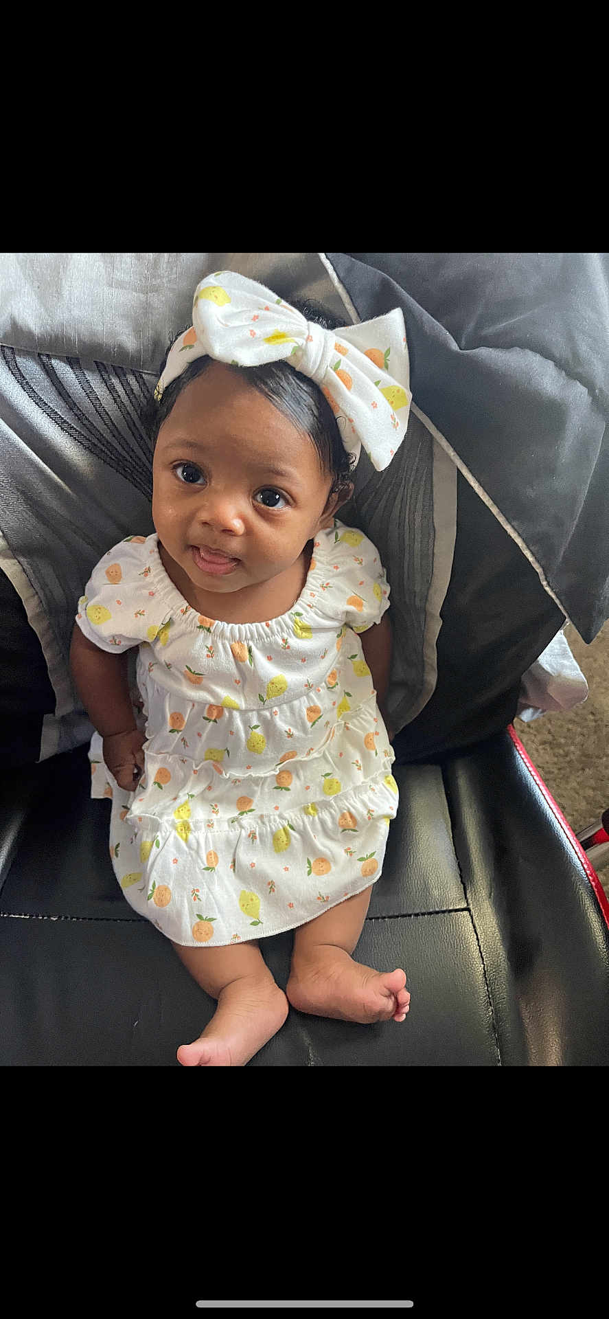 Azari joined the competition — help win amazing prizes! baby, child, infant, dress, headband, bow, fruit_pattern, sitting, black_leather_chair, cute, smiling, tongue_out, curly_hair, indoors, portrait, young_child, comfortable, clothing, apparel, happy