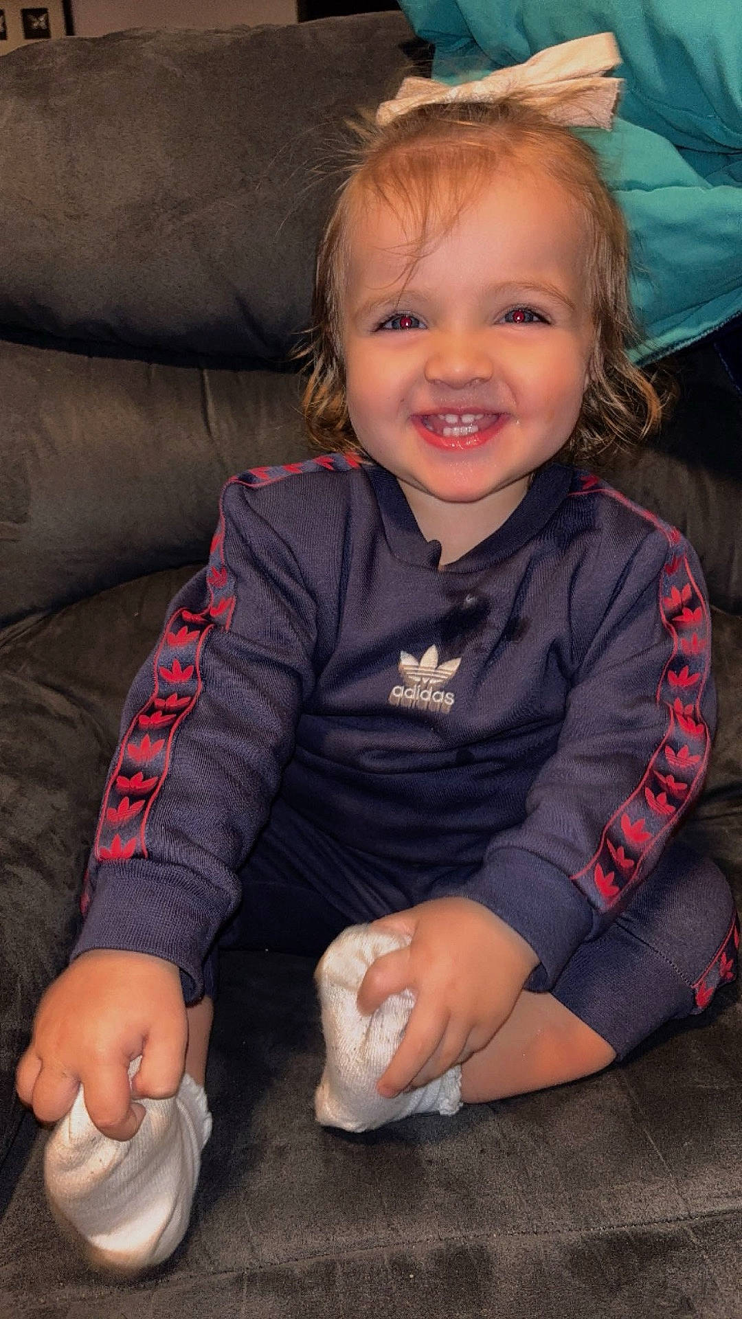 Saige is registered to the contest to win money with this photo: baby, bodypart, clothing, couch, cushion, face, footwear, furniture, happy, head, homedecor, mouth, pants, person, photography, portrait, shirt, sitting, smile, teeth