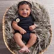 Armani joined the competition — help win amazing prizes! baby, infant, smiling, black_clothing, basket, fur_blanket, floor, cute, small_hands, small_feet, portrait, indoors, cozy, child, happy, resting, soft_texture, curly_hair, looking_away, seated