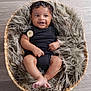 baby, infant, smiling, black_clothing, basket, fur_blanket, floor, cute, small_hands, small_feet, portrait, indoors, cozy, child, happy, resting, soft_texture, curly_hair, looking_away, seated