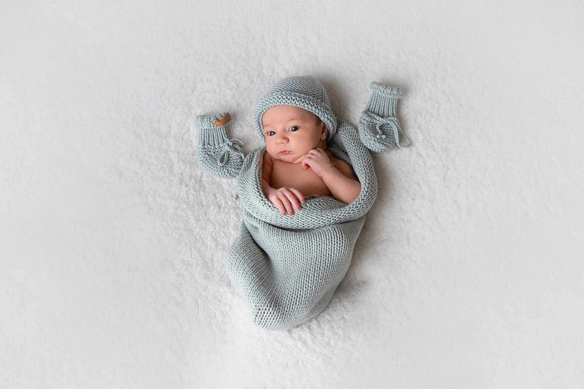 Lou participe au concours pour gagner de l'argent avec cette photo : baby, infant, newborn, knitted, blanket, mittens, hat, wrapped, lying_down, white_background, soft_texture, cute, small_hands, portrait, cozy, sleepwear, warm, resting, face, expression