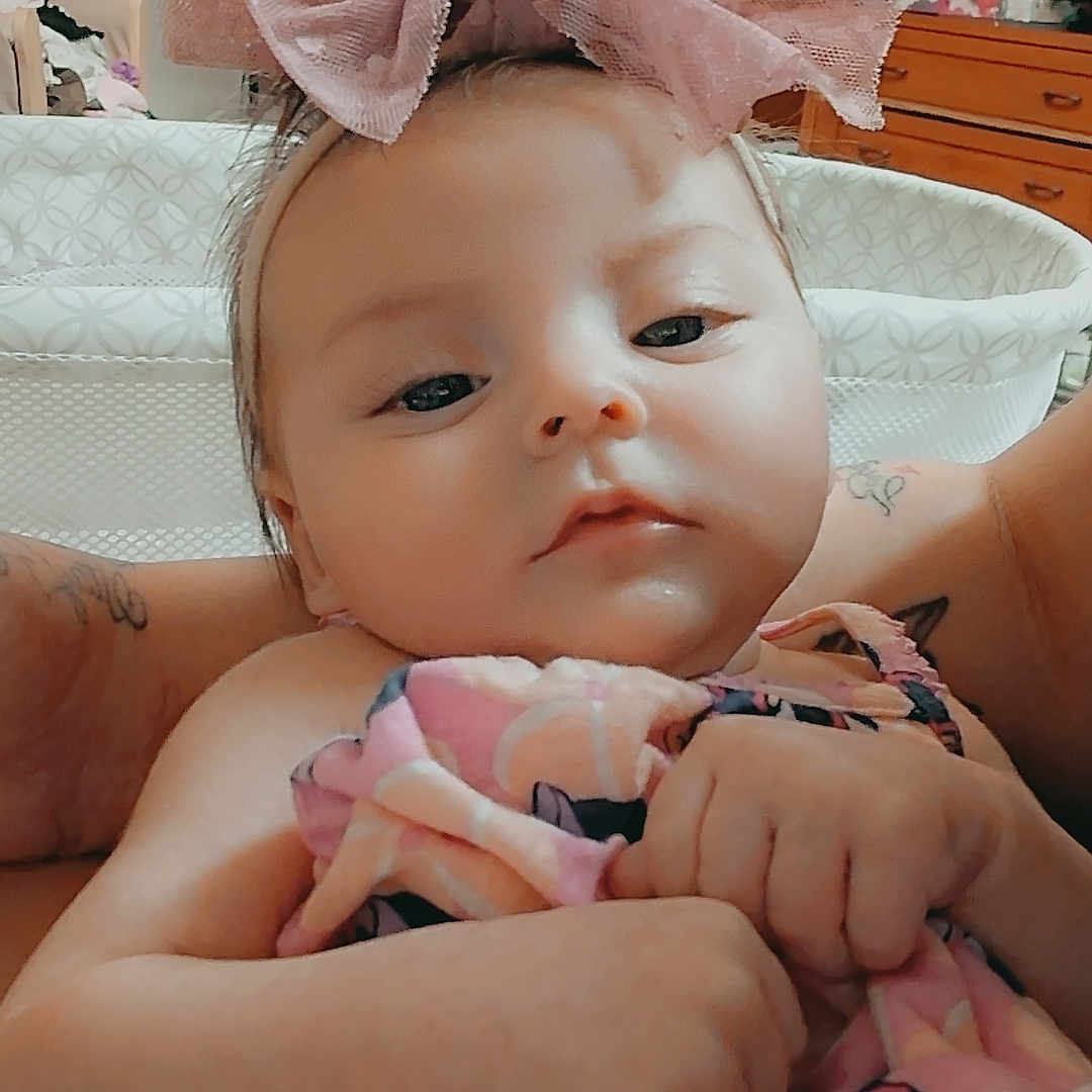 Maleia joined the competition — help win amazing prizes! baby, infant, bow, pink_bow, blanket, tattoo, arms, person, indoor, furniture, dresser, mirror, drawing, wall_art, child, clothing, face, headwear, holding, calm