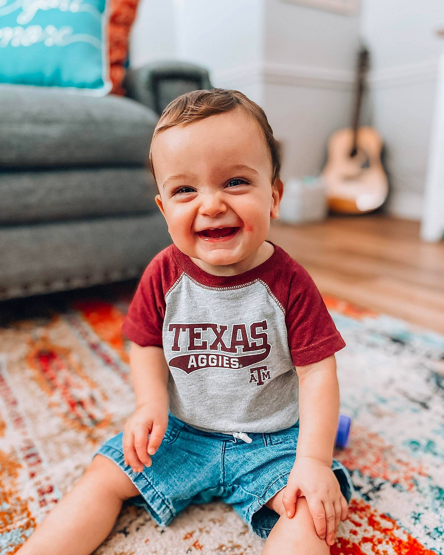 Franklin is registered to the contest to win money with this photo: baby, baby_toddler_clothing, cheek, child, face, facial_expression, flooring, happy, head, joy, people, person, photograph, photography, product, room, sitting, skin, smile, t_shirt