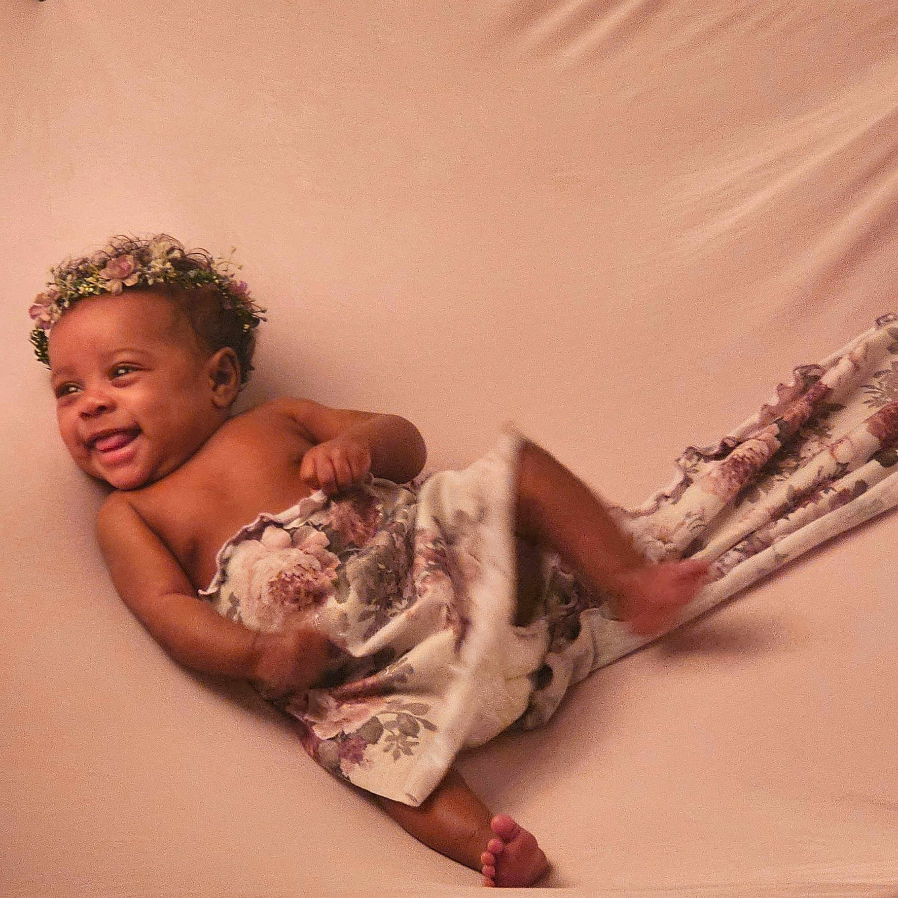 Khaleah joined the competition — help win amazing prizes! baby, bare_chest, blanket, child, cute, fabric, floral_crown, happy, human, indoors, infant, lying_down, one_person, playful, portrait, skin, smiling, soft_lighting, warm_colors, young_child