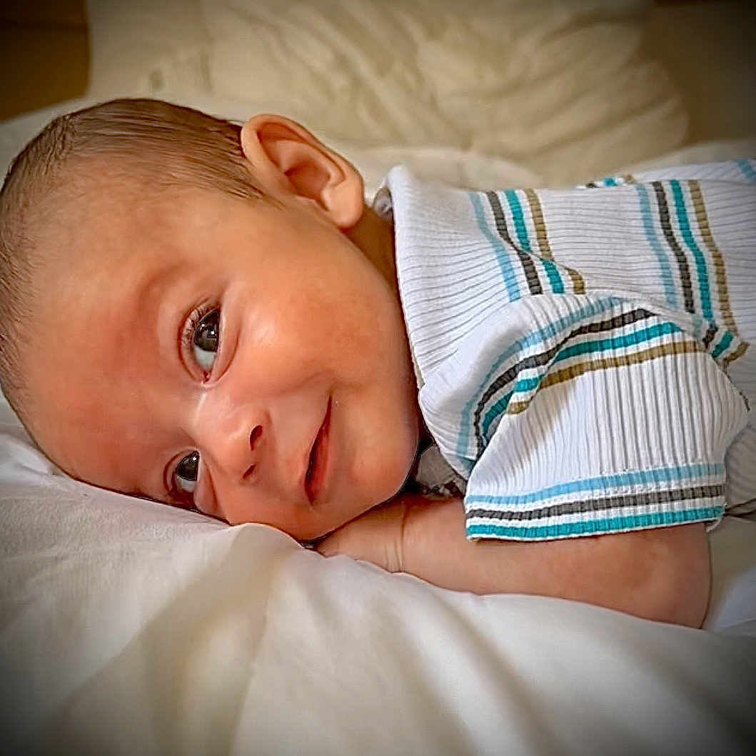Lyandro Martinez a rejoint le concours — aidez-le/la à gagner de superbes lots ! baby, child, closeup, clothing, cute, ear, eyes, face, head, indoors, infant, lying_down, person, portrait, resting, skin, smile, soft_surface, striped_shirt, young