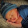 newborn, baby, sleeping, blue_hat, blue_wrap, infant, soft_texture, fluffy_rug, peaceful, closeup, portrait, cute, small_hands, resting, indoors, skin, face, headwear, wrapped, cozy