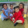 child, children, girl, smiling, playground, outdoor, happy, sitting, dress, casual_clothing, glasses, pigtails, sunny_day, play, friends, group, young, fun, colorful_clothes, grass