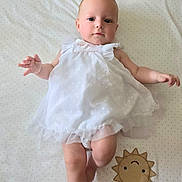 Thaïs a rejoint le concours — aidez-le/la à gagner de superbes lots ! baby, infant, white_dress, crib, polka_dot, hedgehog_illustration, sun_patch, lying_down, cute, child, soft_lighting, indoors, smiling_face, small_hands, barefoot, fabric_texture, bed_sheet, playful, adorable, portrait