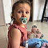 Giovanna participe au concours pour gagner de l'argent avec cette photo : baby, brown_eyes, casual, child, curly_hair, cute, floor, home, indoor, innocent, looking_back, pacifier, person, pink_dress, playtime, plush_toy, sitting, soft_toy, toddler, young_child
